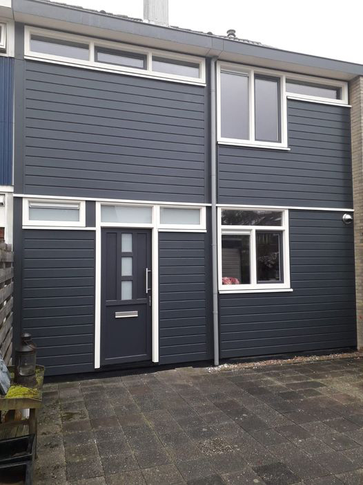 Woning met witte kozijnen, donkere voordeur en antracietkleurige gevelbekleding